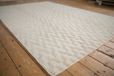 Ivory contemporary rug detail highlighting raised and looped pile with serpent motifs.