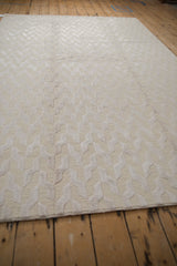 Lustrous ivory and beige contemporary rug with raised serpent design and looped pile.