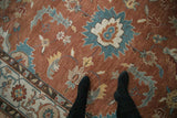 A large floral cross-section in dusty turquoise and ivory on the copper field of a Mahal carpet.