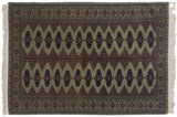 Corner of a vintage Bokhara rug showing its full pile, geometric border, and intact white fringe.