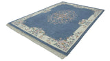 Corner of vintage Indian Aubusson rug: ivory floral border, denim blue field, and fringe.