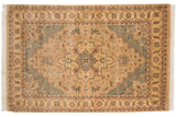 Corner of Indian Heriz rug, with cream fringe, floral vine border, and seafoam green field.
