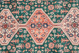 Interconnected cantaloupe and ivory medallions on a forest green Afshar design field of blossoms.