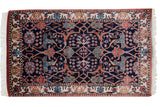 Corner of a vintage Indian rug with intact side cord, ivory fringe, and floral palmette border.