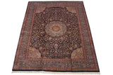 Corner of vintage Ardebil design carpet with navy floral field, blush spandrel, and ivory fringe.