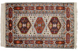 Geometric navy and rust hexagonal medallions on ivory field of vintage Indian Caucasian rug.