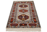 Close-up: vintage Indian rug with geometric rust medallion, hook-and-latch design, and fringe.