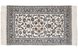 Corner of a vintage Indian Isfahan rug, showing ivory fringe and navy, bronze palmettes.