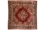 Vintage Sarouk carpet with a floral diamond medallion on a rich ruby red field and navy blue floral borders.