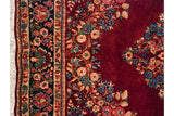 Detail of a vintage Sarouk's floral border, intact side cord, and dense, ruby red pile.
