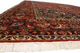 Angled corner view of a vintage Bakhtiari carpet, detailing its even pile, floral borders, and ivory fringe.