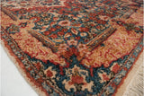 The plush hand-knotted pile and Rococo leaf border of a vintage Persian Kerman rug corner.