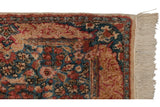 Corner of a vintage Kerman runner showing the even pile, Rococo border, and original ivory fringe.
