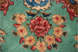 Hand-knotted floral bouquet with blue bird details on the lush ocean-green wool pile.
