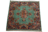Angled perspective of a vintage Kerman square rug with its intricate floral medallion and borders.