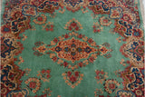 The lush, full pile of a vintage Kerman rug showing scrolling florals on an ocean green field.