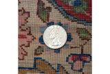 A coin demonstrates the scale of the dense, hand-knotted pile on this vintage Kerman rug.