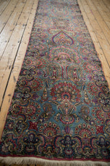 Detailed floral blossoms and budded vines in blue, rose, and purple, displaying rug fringe.