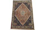 Vintage Abadeh rug with a geometric salmon medallion, navy blue field, and ivory floral border.