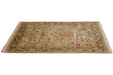 Angled close-up of vintage Indian Arts and Crafts rug corner, featuring flowing olive green border and cinnabar palmettes.