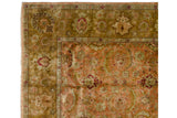 A vintage Agra carpet's corner showing the ochre green palmette border and dusty rose field.