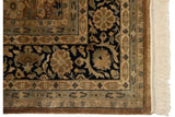 Corner of a vintage Indian carpet highlighting the navy floral border, intact selvage, and ivory fringe.
