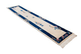Art Deco rug with ivory field, blue butterfly, cobalt border, and pink floral accents.