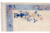 Chinese Art Deco rug corner, ivory field, sky blue border, pink blossoms, dark blue vase motif, fringe.