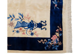 Art Deco rug corner: ivory field, cobalt blue border, blue vased plant, pink florals.