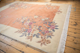 Art Deco rug corner with shallow carved coral, mauve, and ivory floral patterns.