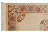 Peking rug corner with cartouche border, floral motifs in mauve, cinnabar, seafoam green, and ivory fringe.