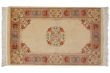Peking rug with roundel medallion, ivory field, floral cartouche border, soft tones.