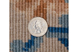 Full pile texture of rug in dusty sandalwood, powder blue, and cobalt, with quarter coin.