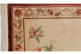 Peking rug corner: fringe, cinnabar red border, ivory field, pink and green floral vine.