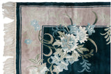 Vintage Art Deco rug corner, showing white fringe, hunter green border, and high-sheen floral blossoms.
