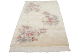 Art Deco rug corner with carved pink, blue floral spray on ivory pile, showing fringe.
