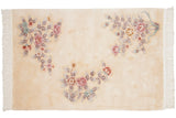 Vintage Art Deco rug detail showcasing pink floral spray, blue-silver leaves, and cream fringe.