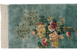 Vintage Japanese Peking rug corner showing ivory fringe, aqua ground, and fuchsia floral-geometric motifs.