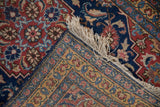 Folded corner of a Tabriz runner contrasts the brick red field with the navy and gold floral border.