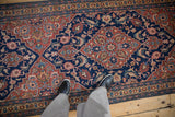 Floral blossoms within the navy blue medallion of a collector's vintage Persian Tabriz runner.