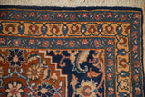 Corner of a hand-knotted Tabriz runner showing the original navy selvage and intricate floral borders.