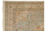 A weaver's insignia within the intricate ivory floral border of a vintage Persian Tabriz carpet corner.