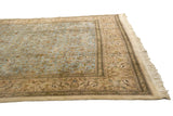 Angled corner of a vintage Tabriz rug showing the pictorial border with meandering deer and trees.