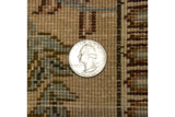 A coin shown for scale on the full, hand-knotted wool pile of a vintage Tabriz carpet.