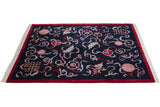 Angled view of a vintage Indian Peking carpet with a navy field and ribboned design elements.