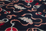 Sprawling cloudband ribbons and leaves with a shallow carved contour on a navy blue wool pile.