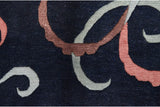 Shallow carved contours define the pale blue and mauve ribbon motifs on the navy blue pile.
