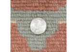 Even full hand-knotted pile of dusty blush and jade green yarns, quarter for scale.