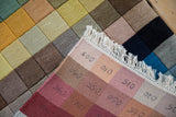 Reverse of a modern Indian rug showing stamped numbers, crisp fringe, and colorful squares.