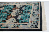 Plush corner of a William Morris rug with teal florals, a decorative border, and cream fringe.